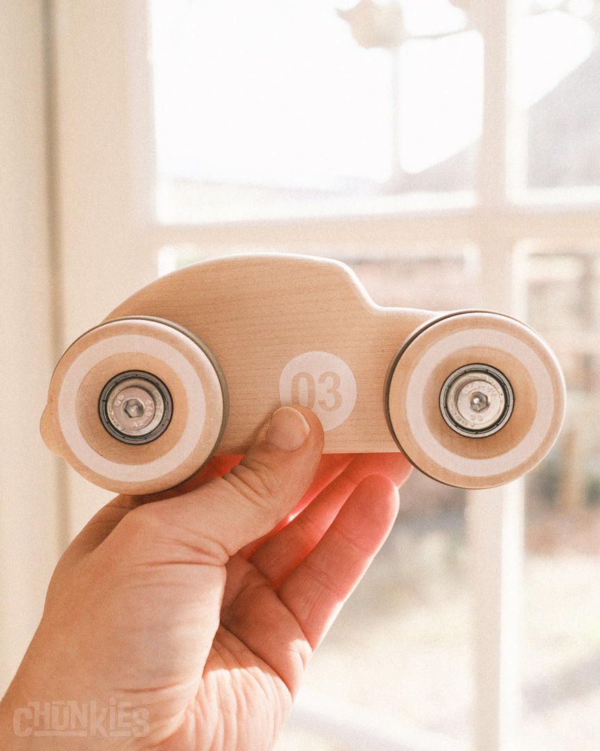 Close side view of the Chunkies model 03 which is shaped like a vintage beetle car. Its giant wooden wheels and solid hardware made for a durable and fast ride. This toy car will go on many adventures